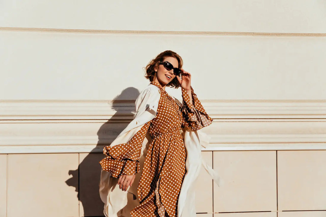 Woman styling a lightweight beige blazer over a summer dress for early fall 2025 fashion trends