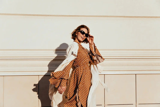 Woman styling a lightweight beige blazer over a summer dress for early fall 2025 fashion trends