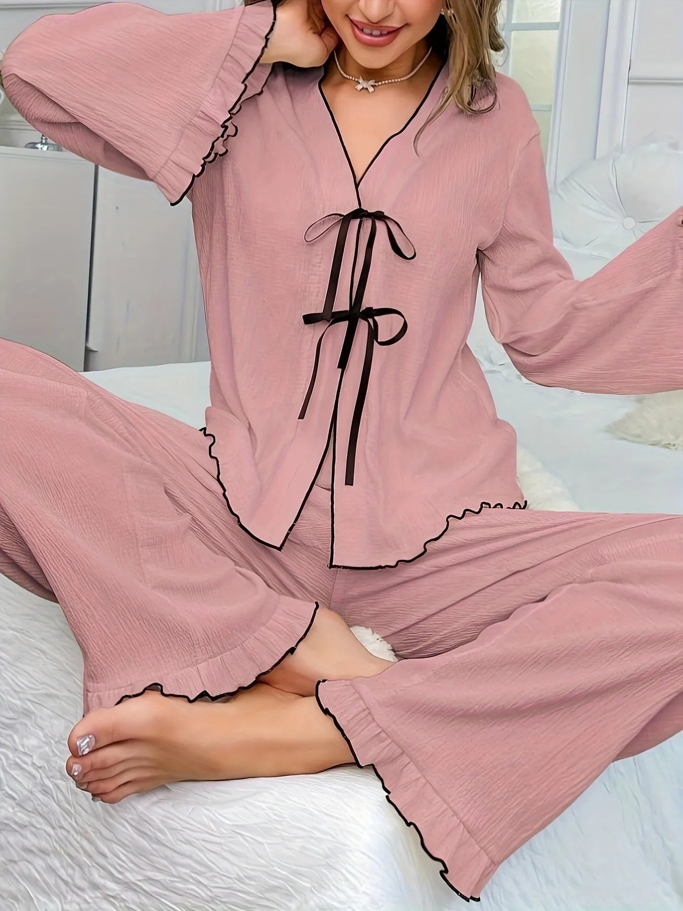 A person wearing pink pajamas with a visible brand logo on a white bed.