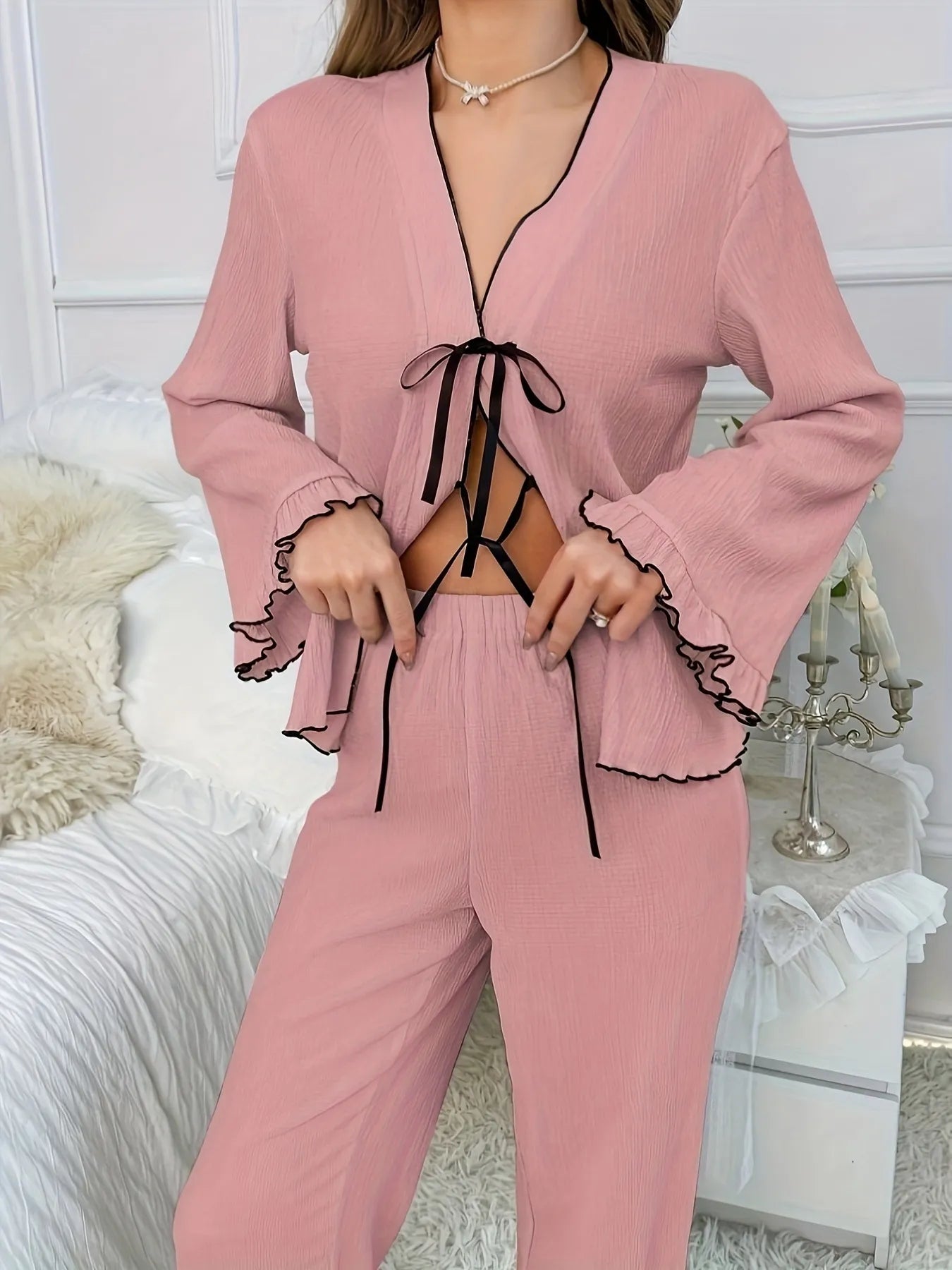 Pink pajama set with black lace details on a white background
