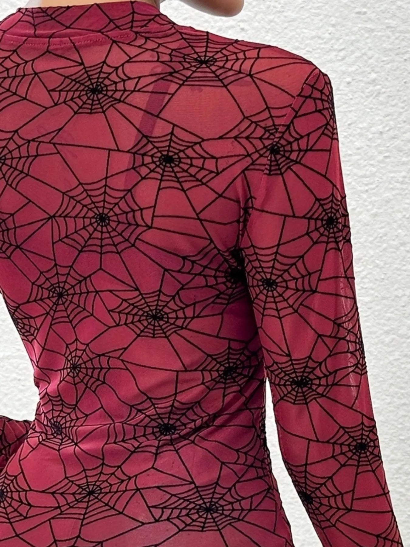 Red dress with black spider web pattern on a white background
